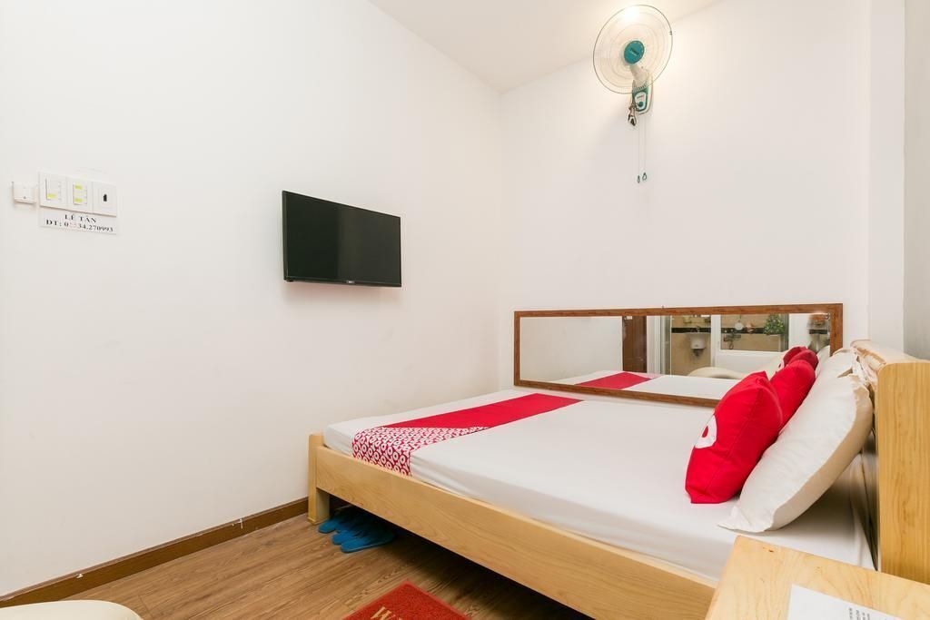 Ein Schlafzimmer mit einem Bett, einem an der Wand befestigten Fernseher und einem Spiegel über dem Bett.