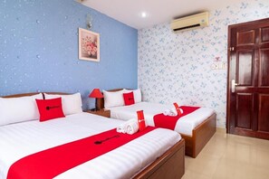 A hotel room with two beds, each with a red bedspread and pillows, a nightstand with a lamp, a wall-mounted air conditioner, and a wooden door. - Nam Bac Hotel by Bay Luxury (Ho Chi Minh City)