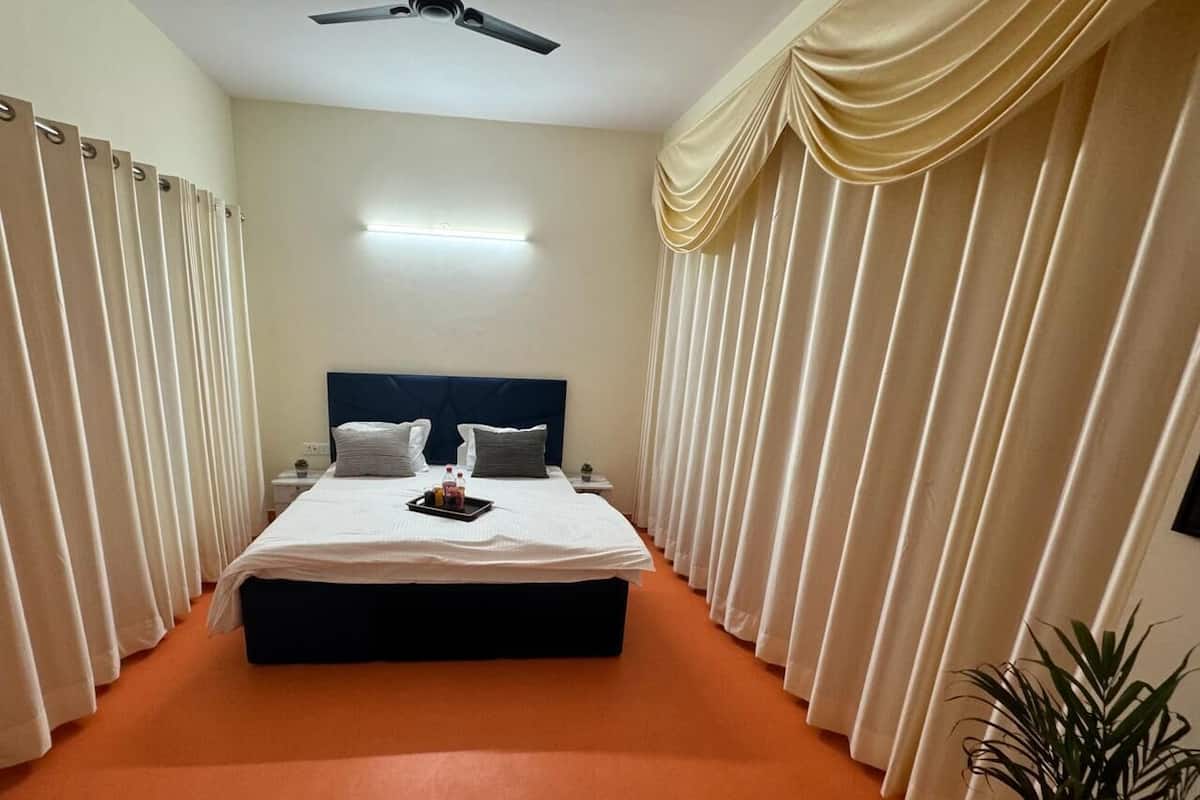 A hotel room with a large bed, a ceiling fan, and curtains.