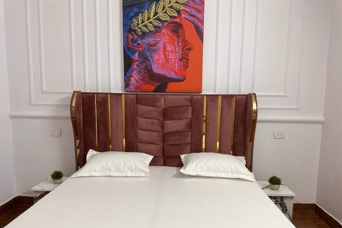 A bed with a tufted headboard, white bedding, and two white pillows.