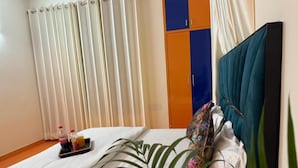 Habitación de hotel con cama, una bandeja con bebidas, una planta y un armario con puertas azules y naranja.