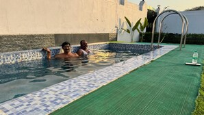 Una piscina con bordes de azulejos y un suelo de cubierta texturizado de color verde.