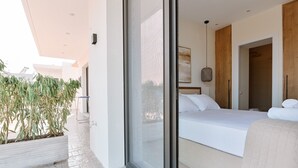 A modern bedroom with a large bed, a glass door leading to a balcony, and a view of the cityscape. - Melior Luxury Villas Preveza (Preveza)