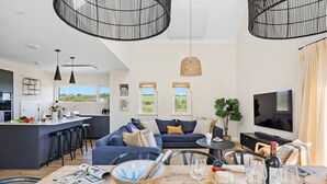 A modern living space with a kitchen, dining area, and a large TV. - 3 The Vista, Willingcott Nr Woolacombe - Hot tub/ Pet friendly/ On-site pool/ EV Charger/ Ecohome (Woolacombe)