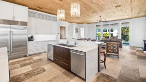 A modern kitchen with a marble island, stainless steel appliances, and wooden ceiling. - Crystal Del Mar. New! Private Pool, Gulf Views (Destin)