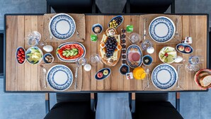 A wooden dining table with blue and white plates, bowls, and glasses, set for a meal. - Bovilla Hotels Salt Yalikavak (Bodrum)