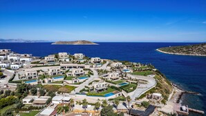 A coastal residential area with modern houses, a small island in the background, and a clear blue sky. - Bovilla Hotels Salt Yalikavak (Bodrum)