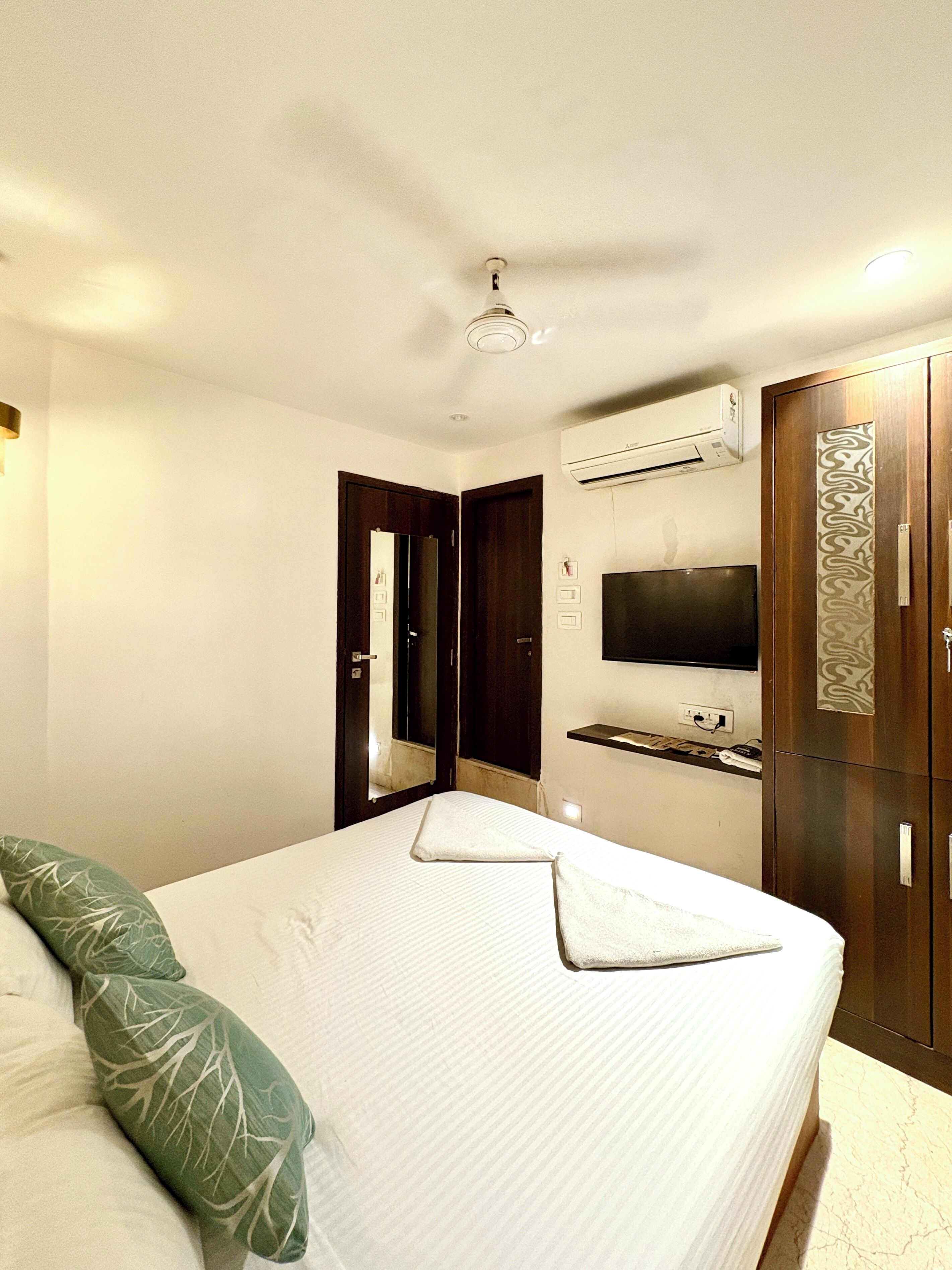 Una habitación de hotel con cama, televisor, aire acondicionado y armario.