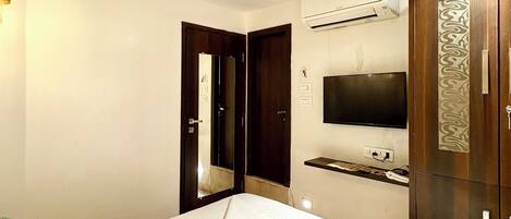 Una habitación de hotel con cama, televisor, aire acondicionado y armario.
