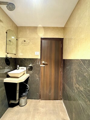 Une salle de bain avec une porte en bois, un lavabo avec un miroir et une douche.