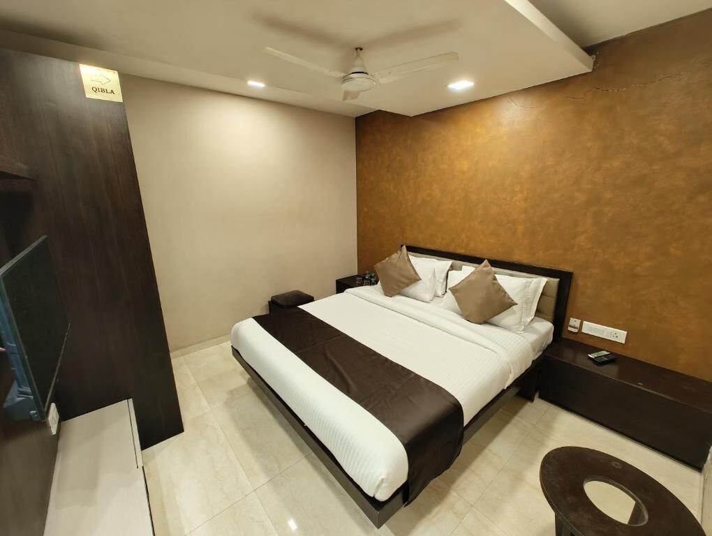 A hotel room with a bed, bedside tables, a ceiling fan, and a sign indicating the room number.