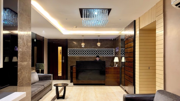 Un vestíbulo moderno con mostrador de recepción, sofás, una araña y una pared con diseño.