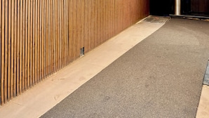 Una zona de recepción con un panel de listones de madera, un letrero que dice "The Majlis Hotel" y una lámpara colgante.
