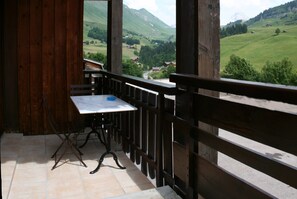 A balcony with a wooden railing, a table, and a chair.