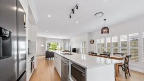 Una cucina moderna con una grande isola, elettrodomestici in acciaio inossidabile e un'area pranzo con tavolo e sedie in legno.