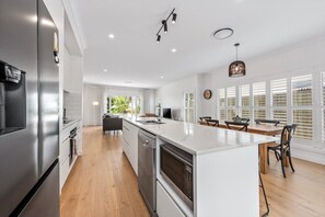 A modern kitchen with a large island, stainless steel appliances, and a dining area with a wooden table and chairs.