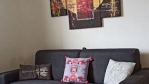Un salon moderne avec un canapé gris foncé, une table basse et un grand tableau abstrait accroché au mur.