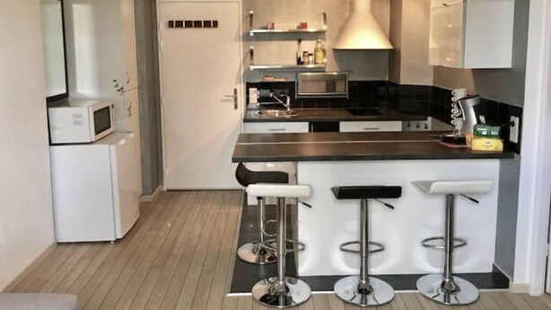 Une cuisine moderne dotée d’un îlot central, de tabourets de bar et d’appareils électroménagers intégrés.