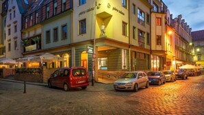 A hotel with a traditional European architectural style, featuring a corner building with a statue on the facade, multiple windows, and a cobblestone street in front. - LeoApart (Wroclaw)