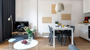 A modern living room with a dining area, a flat-screen TV, a coffee machine, and a small kitchen. - LeoApart (Wroclaw)