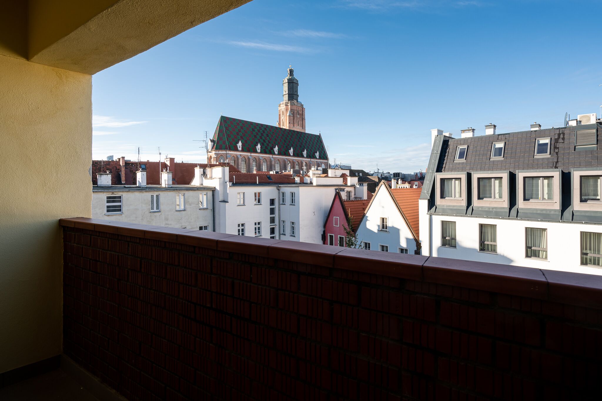 Un balcon offrant une vue sur le paysage urbain, avec notamment une tour imposante et divers bâtiments.