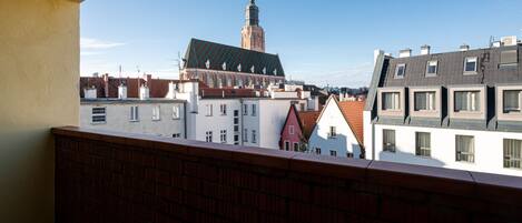 Un balcon offrant une vue sur le paysage urbain, avec notamment une tour imposante et divers bâtiments.