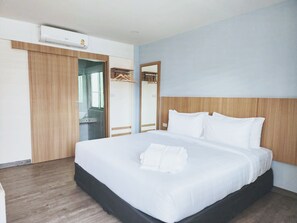 A hotel room with a large bed, a wooden wardrobe, a mirror, and an air conditioning unit. - Beyond 21 Hotel (Khon Kaen)