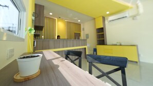 A modern kitchen with a yellow and white color scheme, a wooden table, and a potted plant.