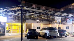 A parking area with several cars parked under a covered structure.