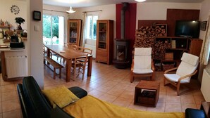A cozy living room with a sofa, chairs, a dining table, a fireplace, and a television.