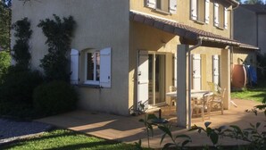 A two-story house with a patio area, a sliding glass door, and a small outdoor seating area.