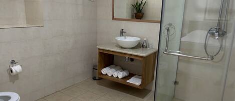 A modern bathroom with a glass-enclosed shower, a white sink, and a toilet.