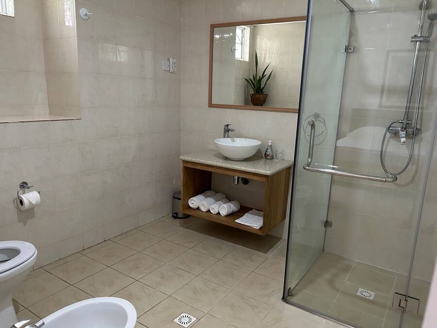 Un baño moderno con ducha de vidrio, lavamanos blanco y retrete.