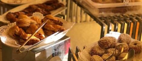 Un bufé con diversos alimentos, incluyendo pasteles y postres, dispuestos en bandejas.