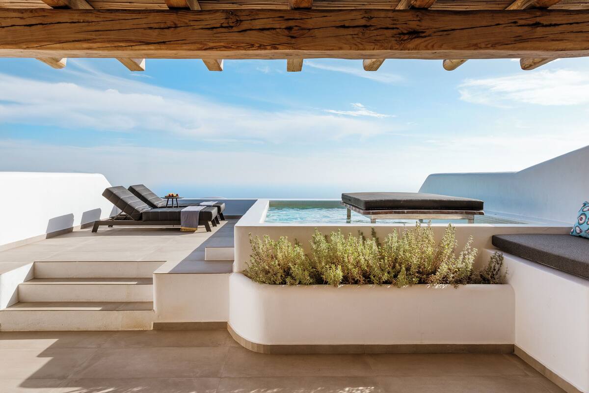 A rooftop terrace with a pool, lounge chairs, and a wooden pergola.