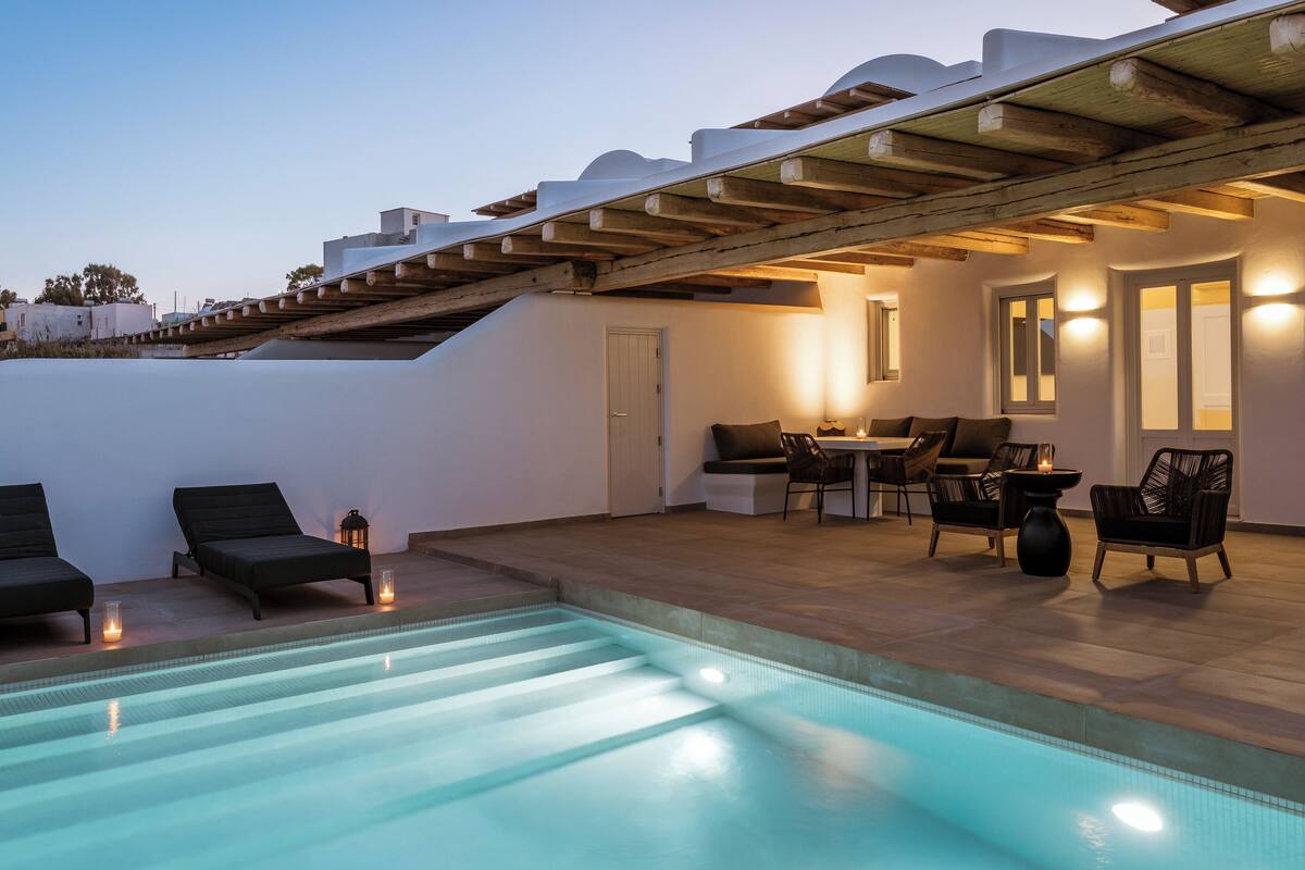A rooftop pool area with lounge chairs and a dining set.