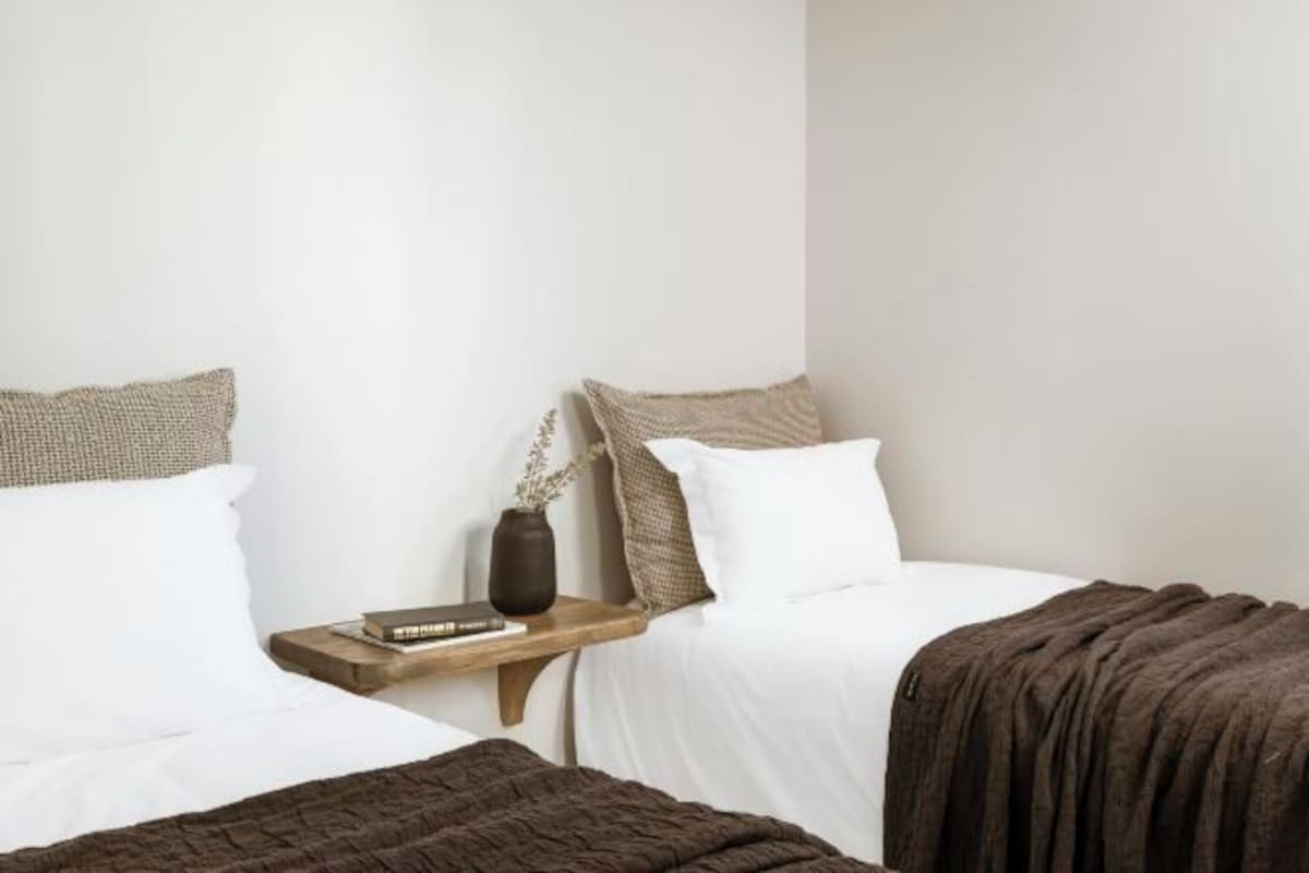 A bedroom with two beds, a nightstand, a vase, and a book.