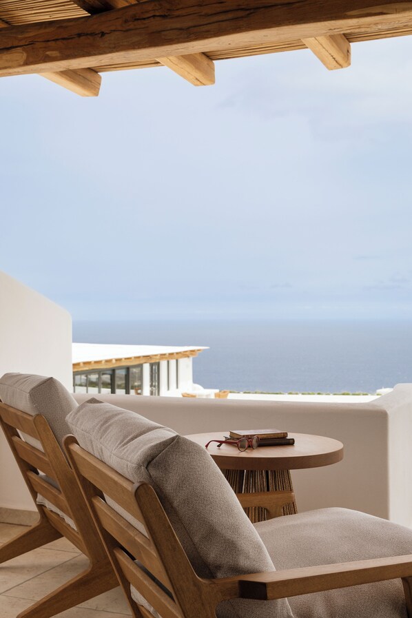 A wooden chair and table on a balcony with a view of the sea. - NĒRO Hotel (Santorini)