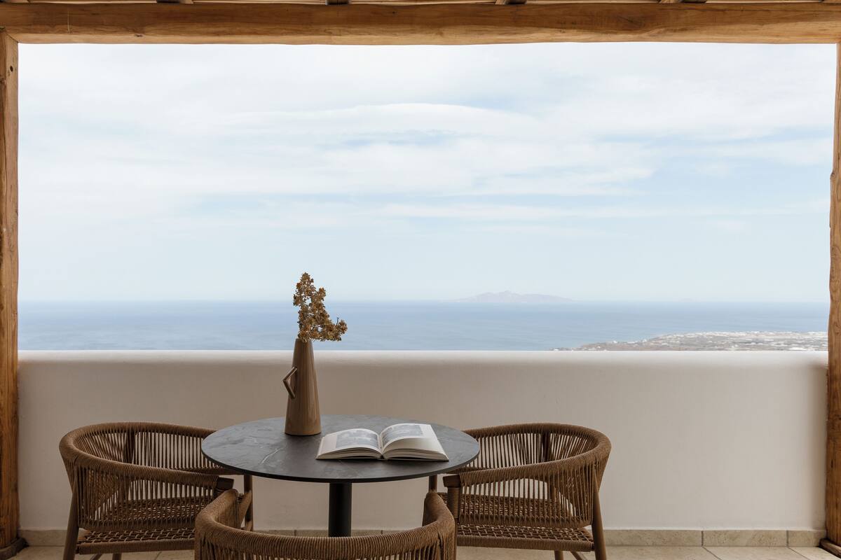 A balcony with wicker chairs, a round table, and an open book.