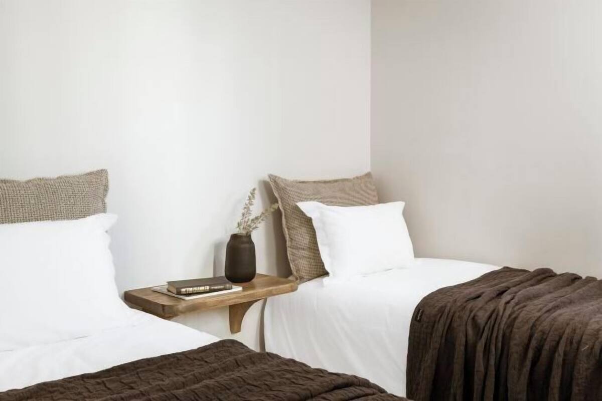 A bedroom with two beds, a nightstand, a vase, and a book.