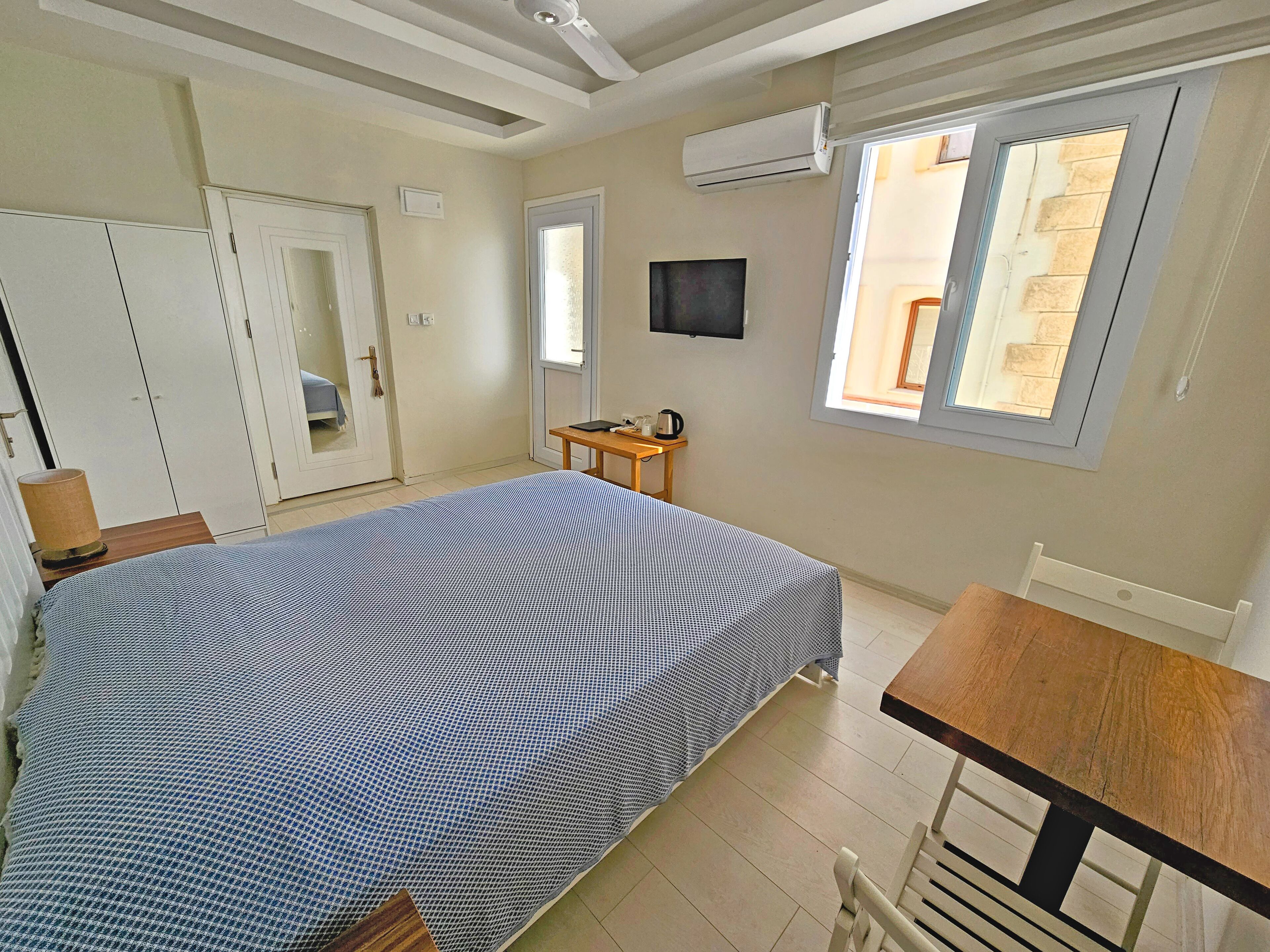 Un dormitorio con cama, escritorio, silla, armario y ventana.