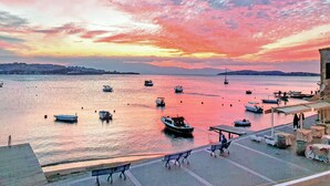 Une scène au bord de l’eau avec des bateaux, un quai et un coucher de soleil.