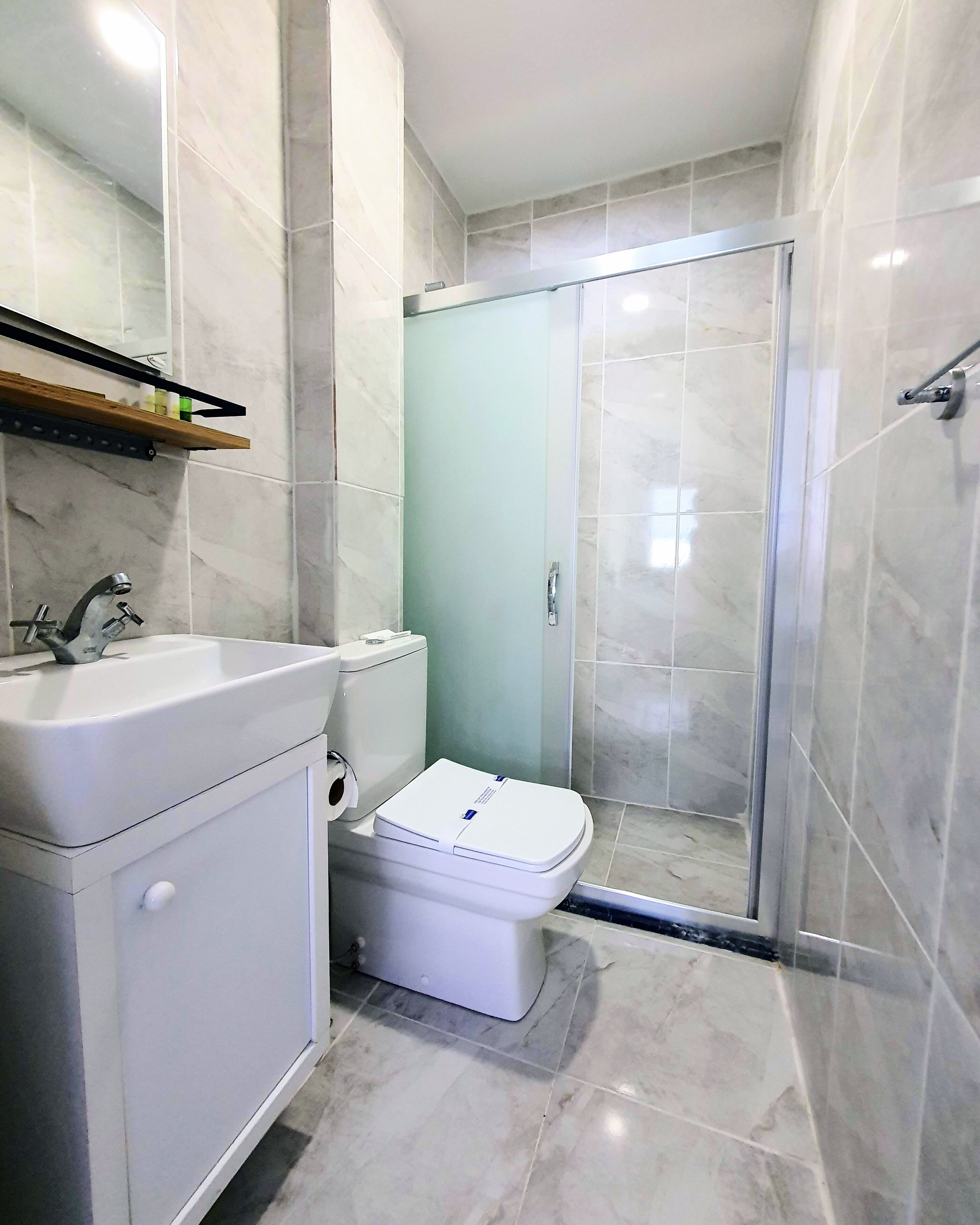 Ein Badezimmer mit weißem Waschbecken, Toilette und Duschkabine aus Glas.