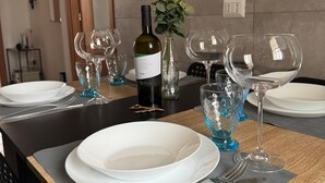 Mesa para comer preparada con platos blancos, copas azules y una botella de vino.