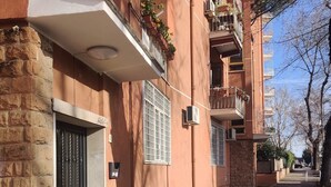 Una calle estrecha con una hilera de edificios de color terracota, cada uno con un balcón y una ventana pequeña.