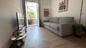 Una sala de estar moderna con un sofá gris, un televisor y una planta.