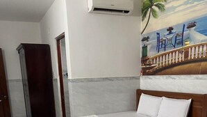 A hotel room with two beds, a painting of a beach scene, and an air conditioning unit on the wall. - Ngoc Yen Hotel by Bay Luxury (Ho Chi Minh City)