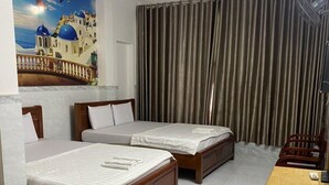 A hotel room with two wooden beds, a desk, and a large window with curtains. - Ngoc Yen Hotel by Bay Luxury (Ho Chi Minh City)