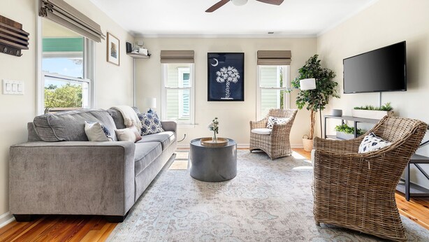 A living room with a gray sofa, wicker chairs, a round coffee table, and a ceiling fan. - Crescent Cottage | Walk to Republic + Prohibition (Charleston)