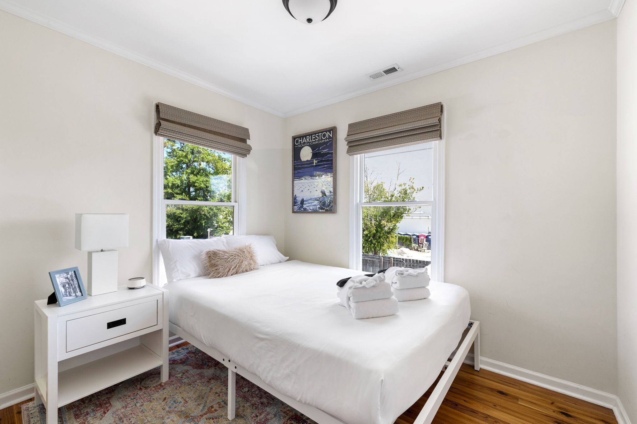 A bedroom with a bed, nightstand, and window with a view of trees.